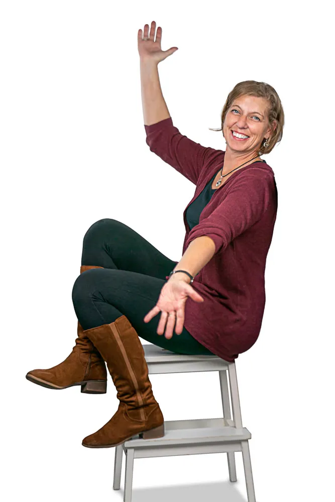 Ingrid Pyka sitting in a chair with her right arm up in the air and left pointing down -